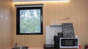Une cuisine compacte avec une fenêtre, une machine à café, un four à micro-ondes et une pancarte sur laquelle on peut lire : « Bienvenue à Rocky Creek Escape ».