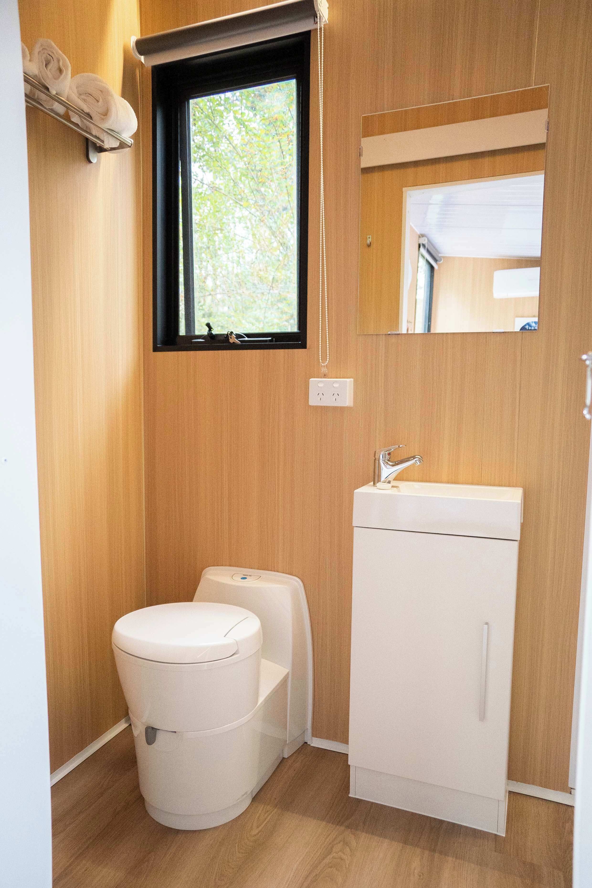 Une petite salle de bain comprenant des toilettes, un lavabo et une fenêtre.