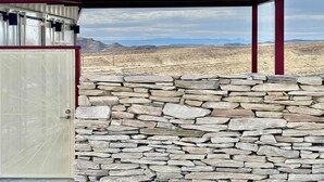A stone wall with a metal structure and a door. - Fossil Knob Ridge -Sierra Vista: Ultra Modern (Terlingua)