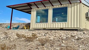 A container-style building with a metal roof and large windows. - Fossil Knob Ridge -Sierra Vista: Ultra Modern (Terlingua)
