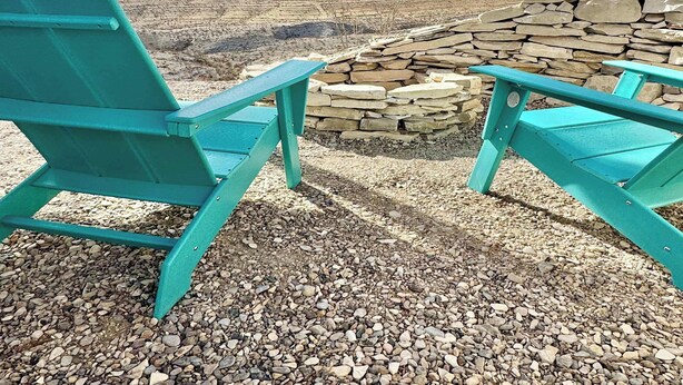 Turquoise Adirondack chairs facing a stone fire pit with a rocky landscape and distant mountains in the background. - Fossil Knob Ridge -Sierra Vista: Ultra Modern (Terlingua)