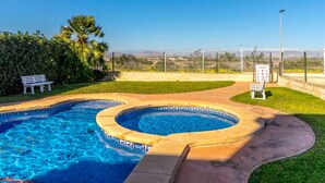 A swimming pool with a curved design, surrounded by a fence, a bench, and a signboard.