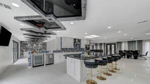 Una cucina moderna con isola centrale, sgabelli da bar e zona pranzo con sedie.