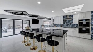 Una cucina moderna con isola centrale, sgabelli da bar e una grande finestra.
