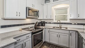 A modern kitchen with white cabinets, a stainless steel microwave, a built-in oven, and a large window. - Majestic Retreat - Navarre Townhouse With Bay Access, Garage Community Pool, Kayak, and Paddleboard (Navarre)