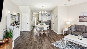 A modern kitchen with white cabinets, a dining area with a round table and chairs, a gray sofa, and a ceiling fan. - Majestic Retreat - Navarre Townhouse With Bay Access, Garage Community Pool, Kayak, and Paddleboard (Navarre)