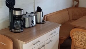 Et kompakt tekøkken med kaffemaskine, brødrister og elkedel på en træbordplade.