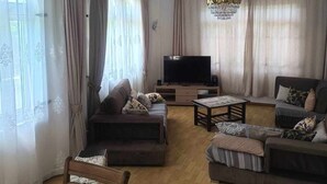 A living room with a sofa set, a TV, and a chandelier.