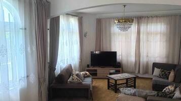 Un salon comprenant un ensemble de canapés, un téléviseur et un lustre.