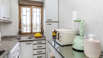 Een koelkast, een microgolfoven, een oven, kookgerei, borden en bestek