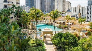 A resort with a central pool, surrounded by palm trees and modern buildings. - Level 45 Luxury Sub-Penthouse in Surfers (Surfers Paradise)
