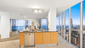 A modern kitchen with a central island, large windows, and a city view. - Level 45 Luxury Sub-Penthouse in Surfers (Surfers Paradise)