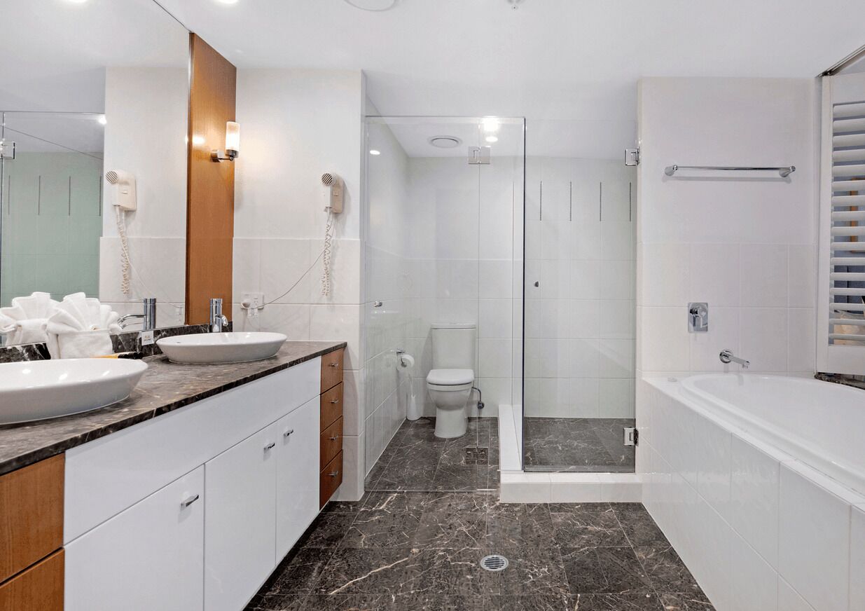 Un bagno moderno con uno specchio grande, due lavandini, un WC, una doccia e una vasca da bagno.