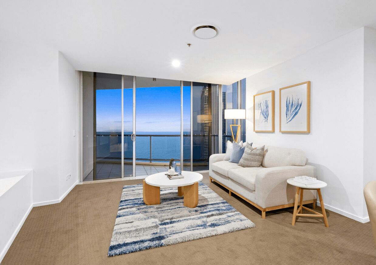 A modern living room with a large sliding glass door leading to a balcony with a city view.