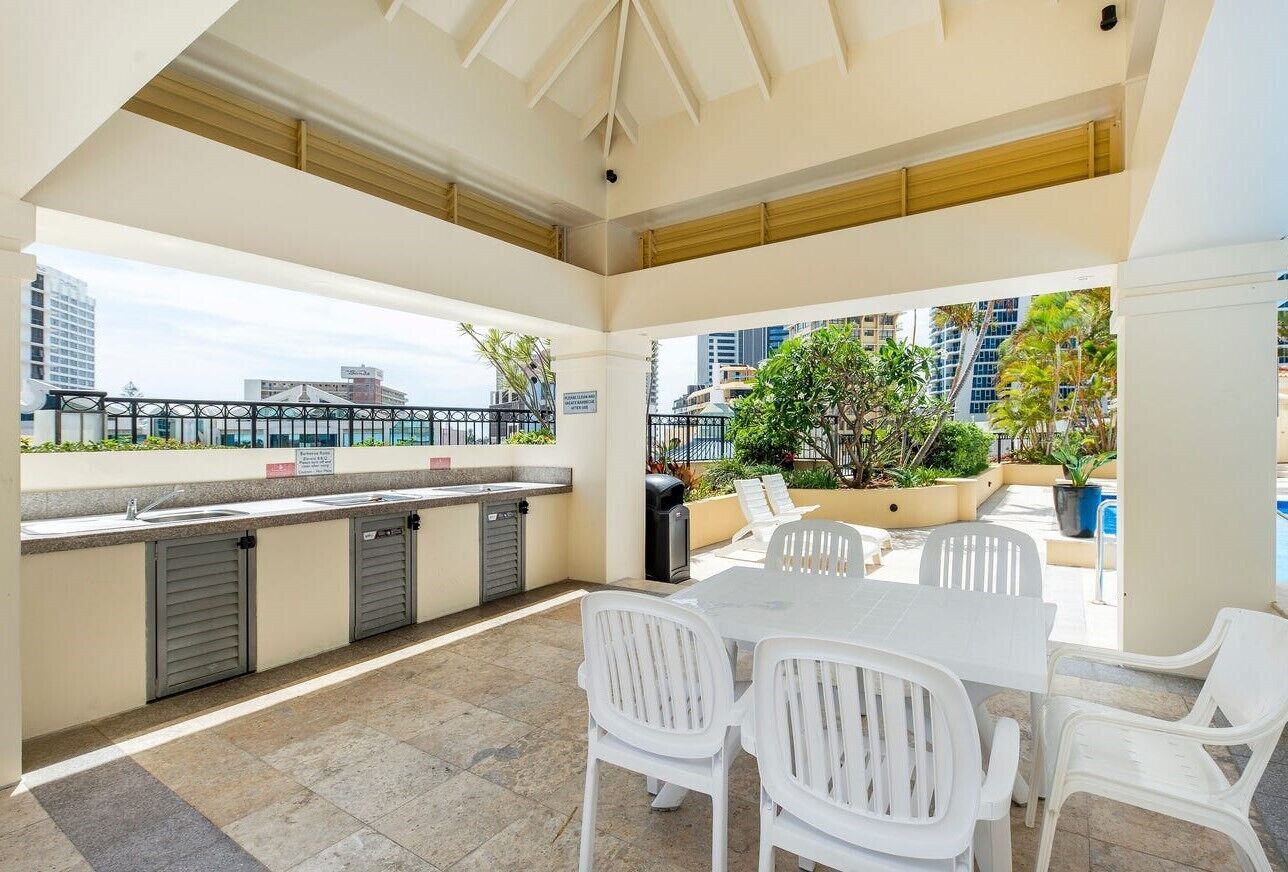 An outdoor patio with a table and chairs, a sink, and a view of the city skyline.
