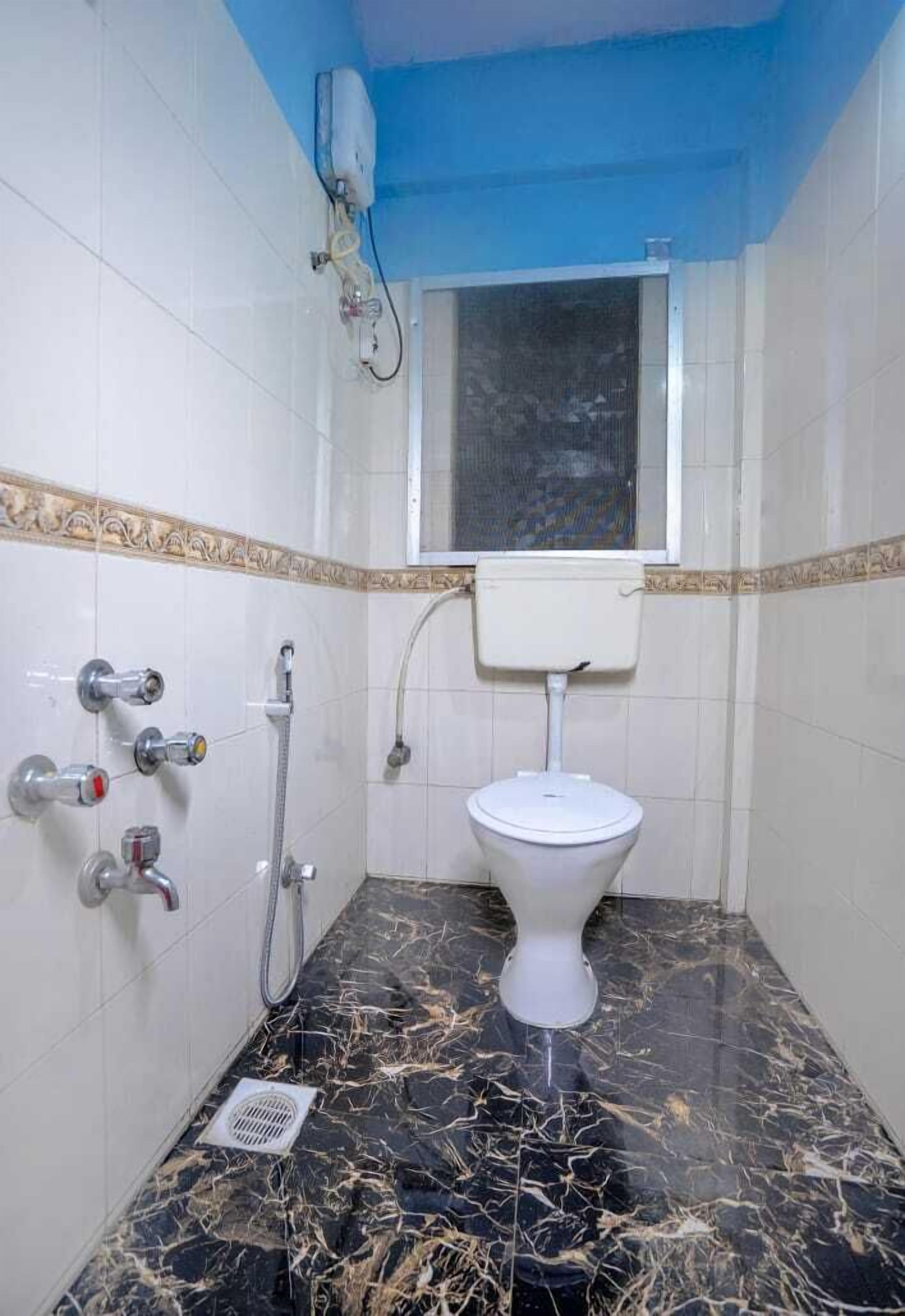 A bathroom with a toilet, shower, and a window above the toilet.