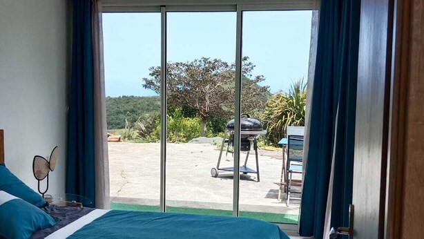 A bedroom with a large bed, a view of the outdoors, and a sliding glass door leading to a patio area.