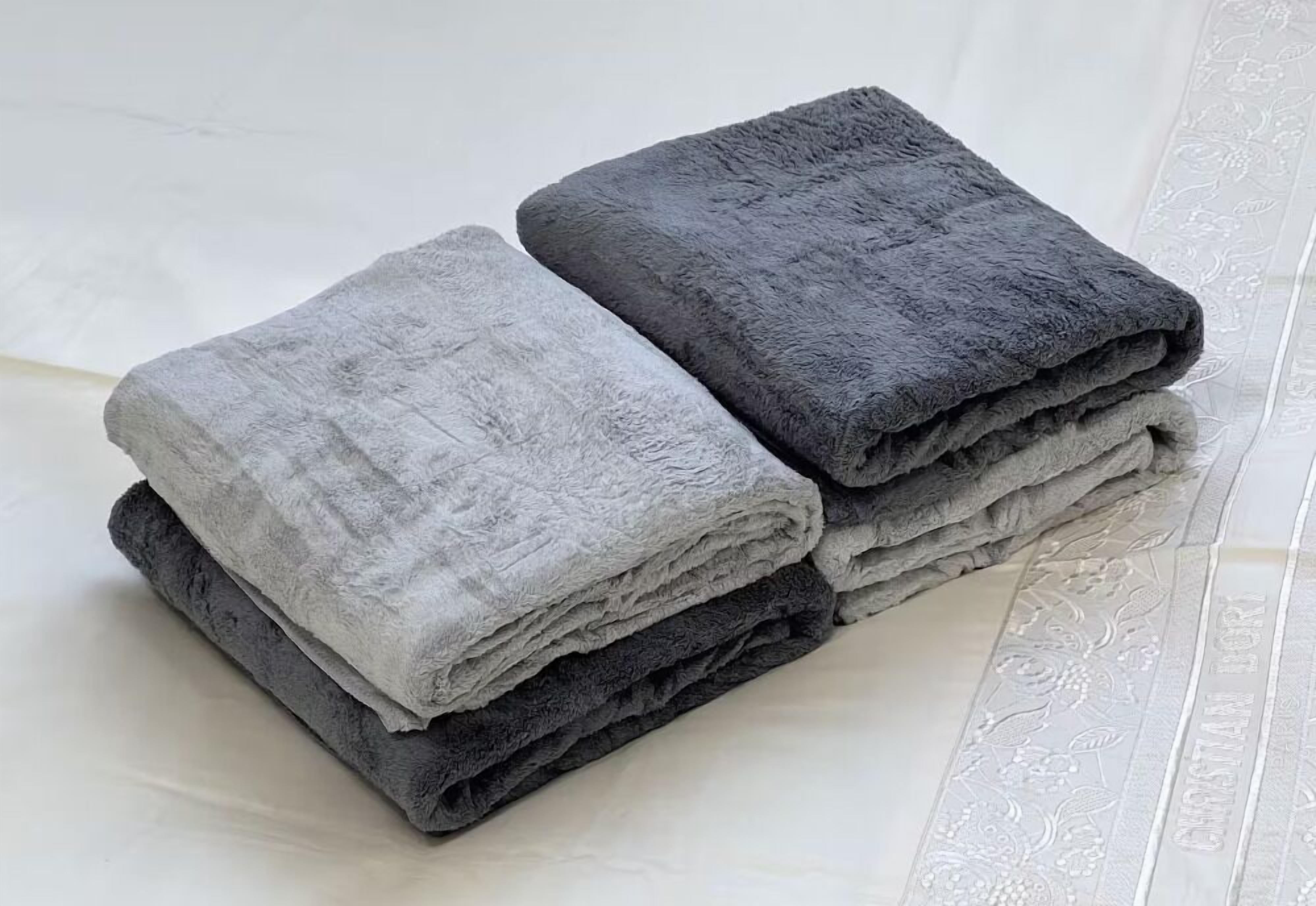 A stack of folded towels in varying shades of gray.