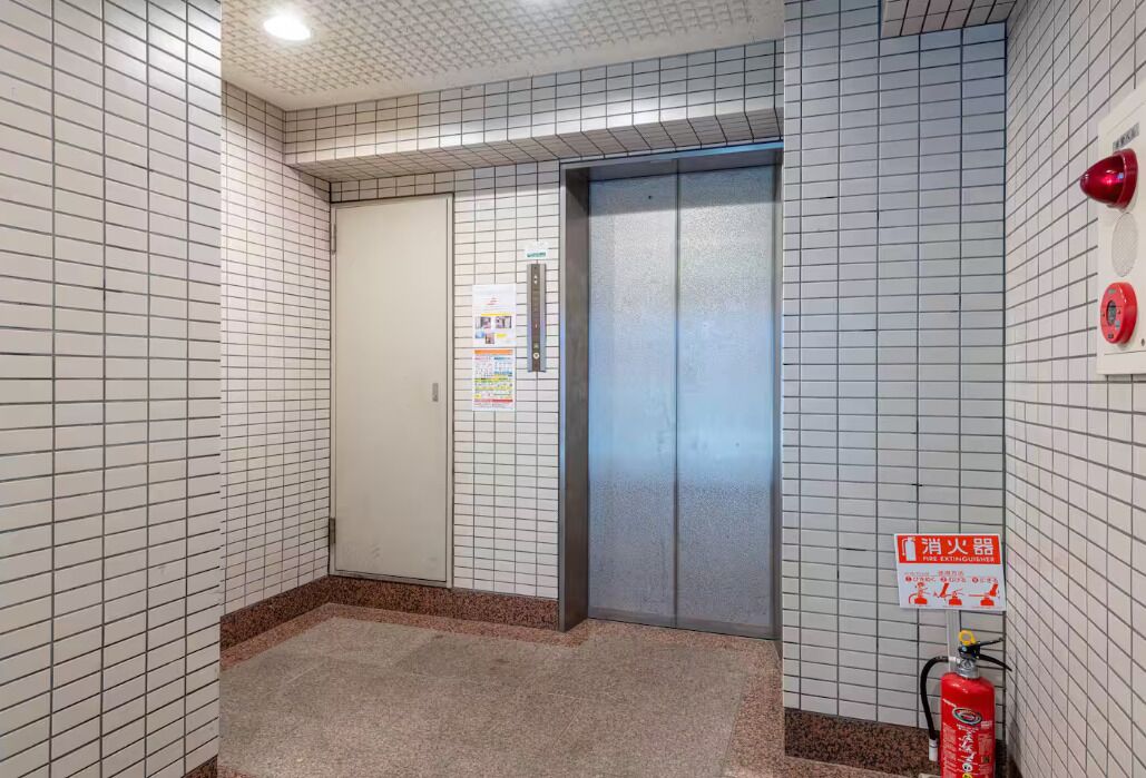 A tiled hallway with a door and an elevator.