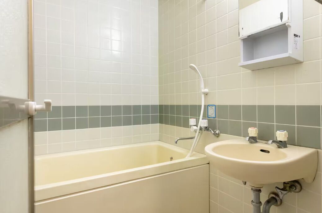 Een badkamer met een bad, een wastafel en een douchekop.