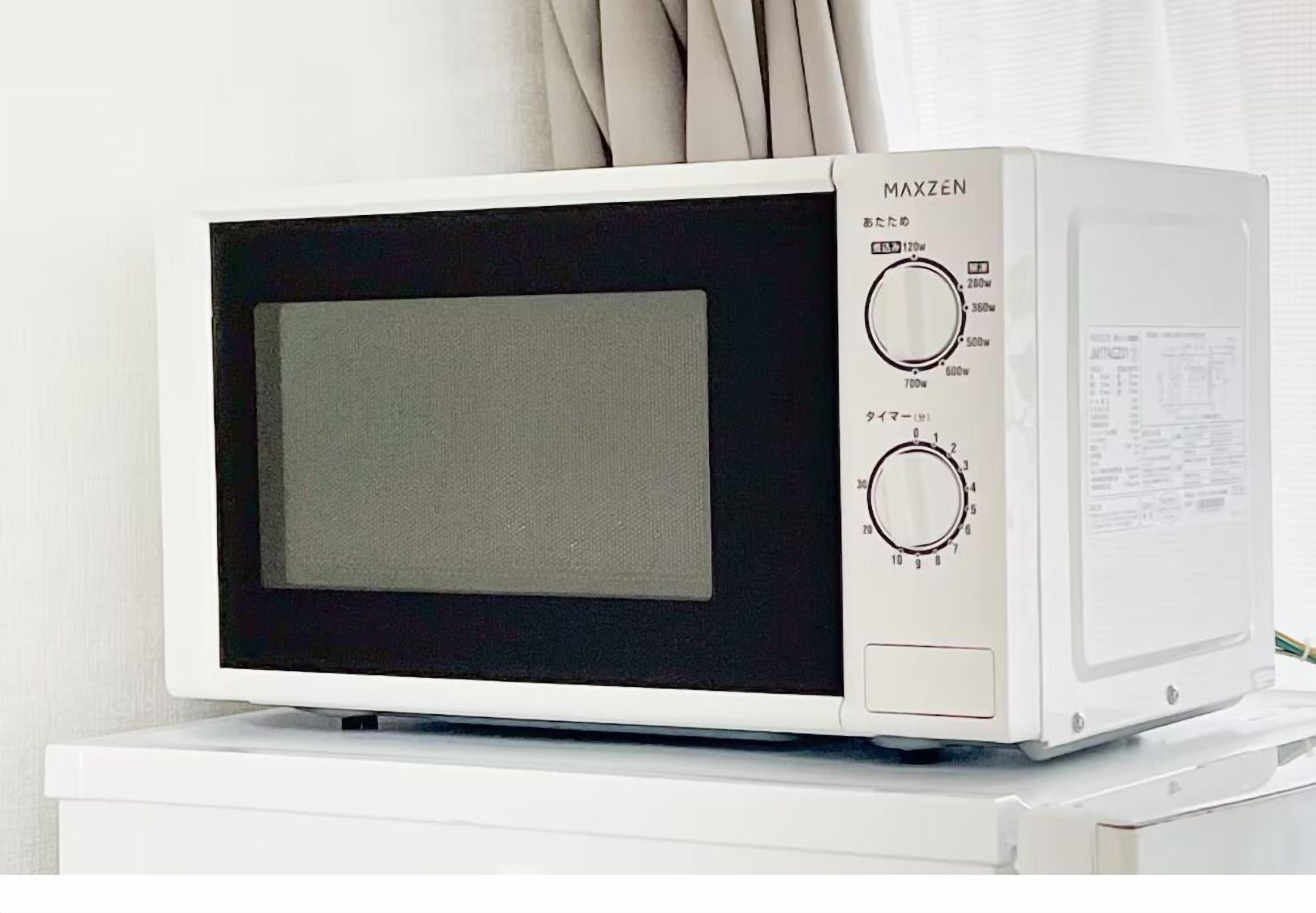 Un microondas blanco con pantalla y panel de control negros, sobre una superficie blanca.