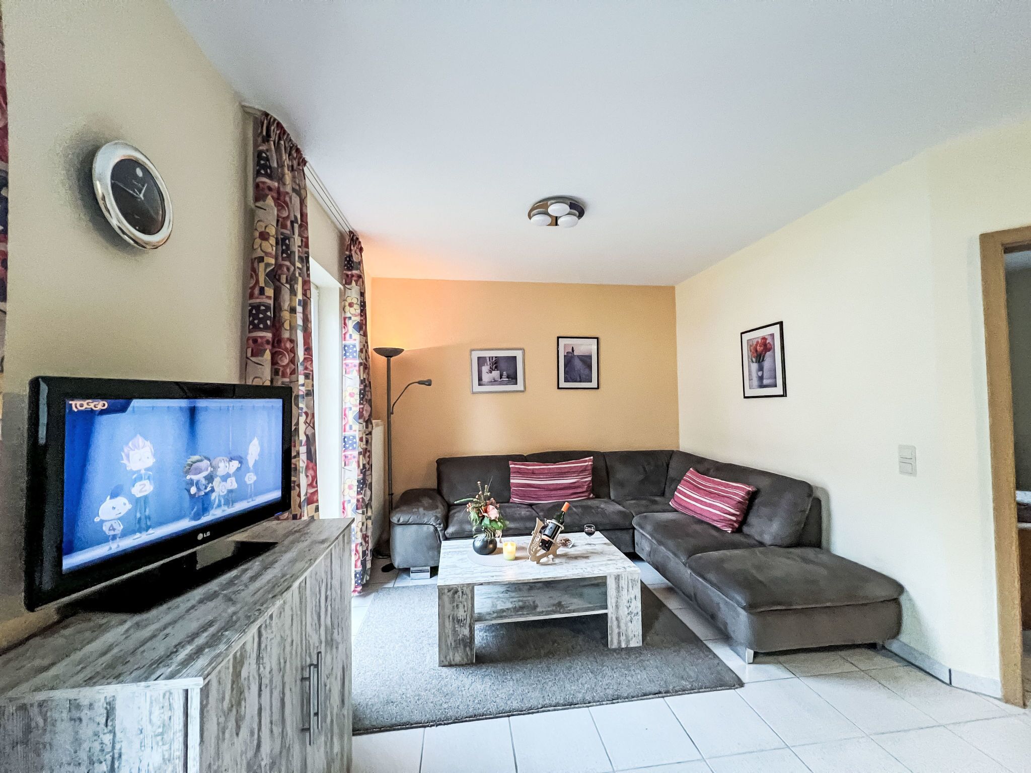 Una sala de estar con televisor, sofá, mesa de centro y lámpara.