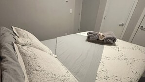 Ein Einzelbett mit Steppdecke, einem gefalteten Handtuch und einem Nachttisch.