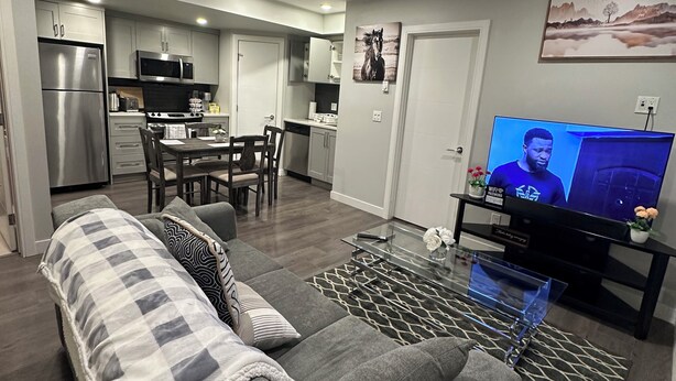 Ein modernes Wohnzimmer mit grauem Sofa, Couchtisch und Fernseher.