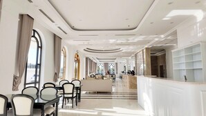 A spacious hotel lobby with a reception desk, seating area, and large windows allowing natural light. - SEDONA Hotel Viet Yen (Viet Yen)