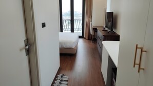 A hotel room with a bed, a desk, a TV, and a balcony with curtains. - SEDONA Hotel Viet Yen (Viet Yen)