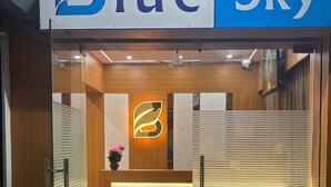 Entrada de hotel con mostrador de recepción, un logotipo en la pared y un mostrador de check-in.