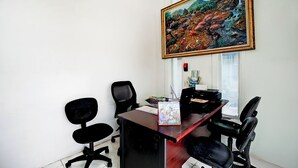 A room with a wooden desk, black office chairs, a large framed painting, and a window with blinds. - Hotel O Tegalsari Near Tunjungan Plaza (Surabaya)
