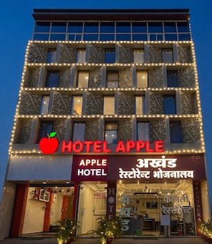 Un hotel de varios pisos con un llamativo logotipo de manzana y señalización que dice 'Hotel Apple'.