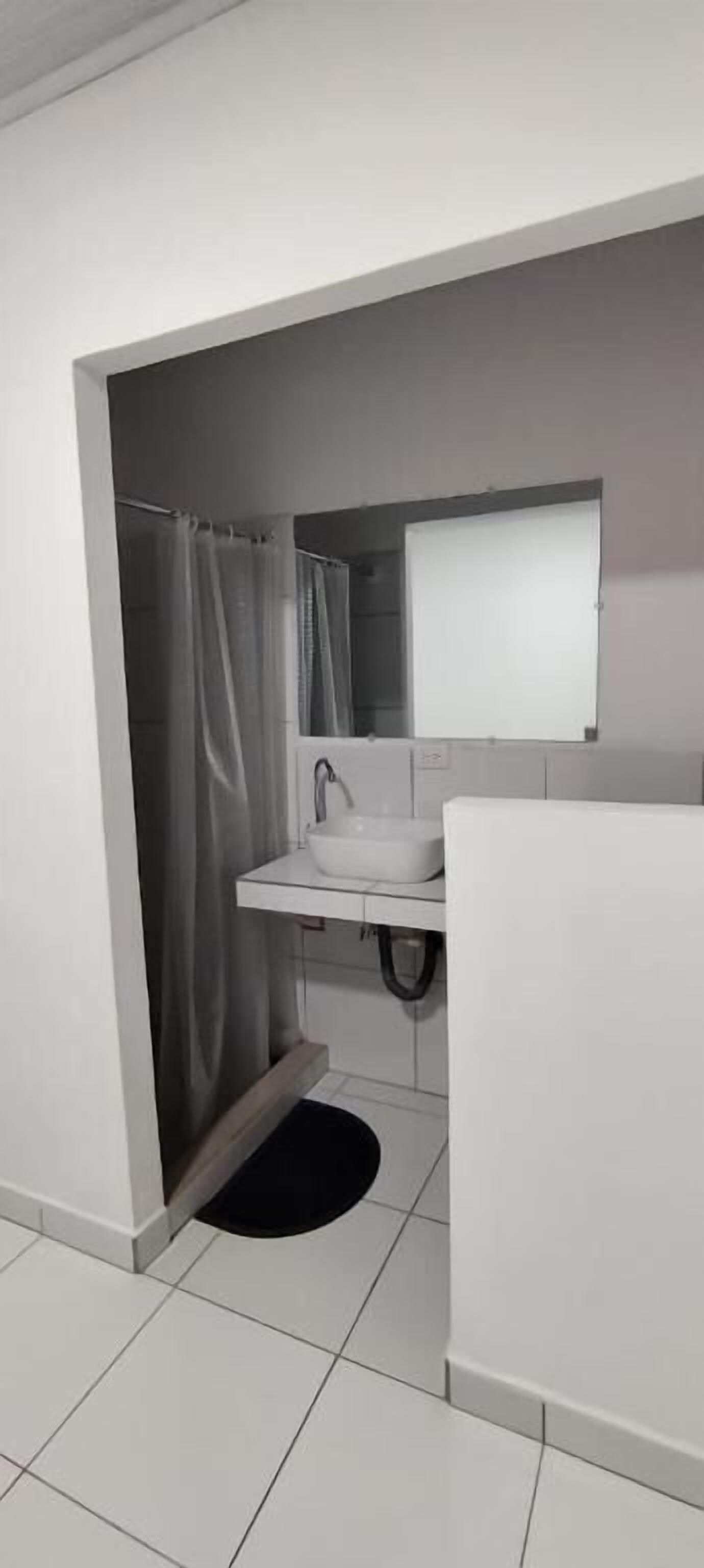 A bathroom with a white sink, a mirror, and a shower curtain.