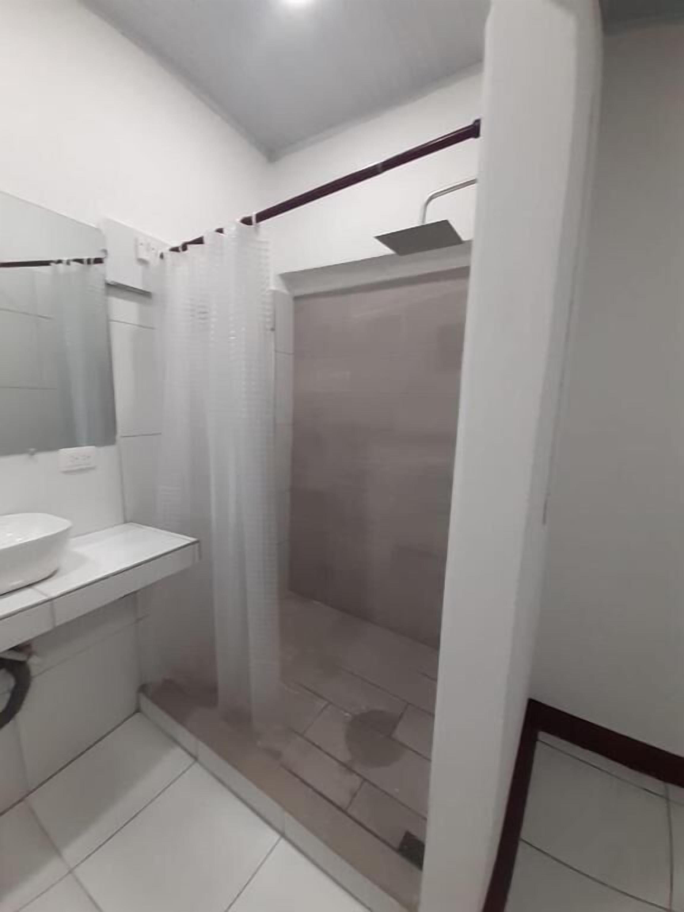 A bathroom with a white sink, mirror, and shower enclosure.