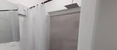 A bathroom with a white sink, mirror, and shower enclosure.