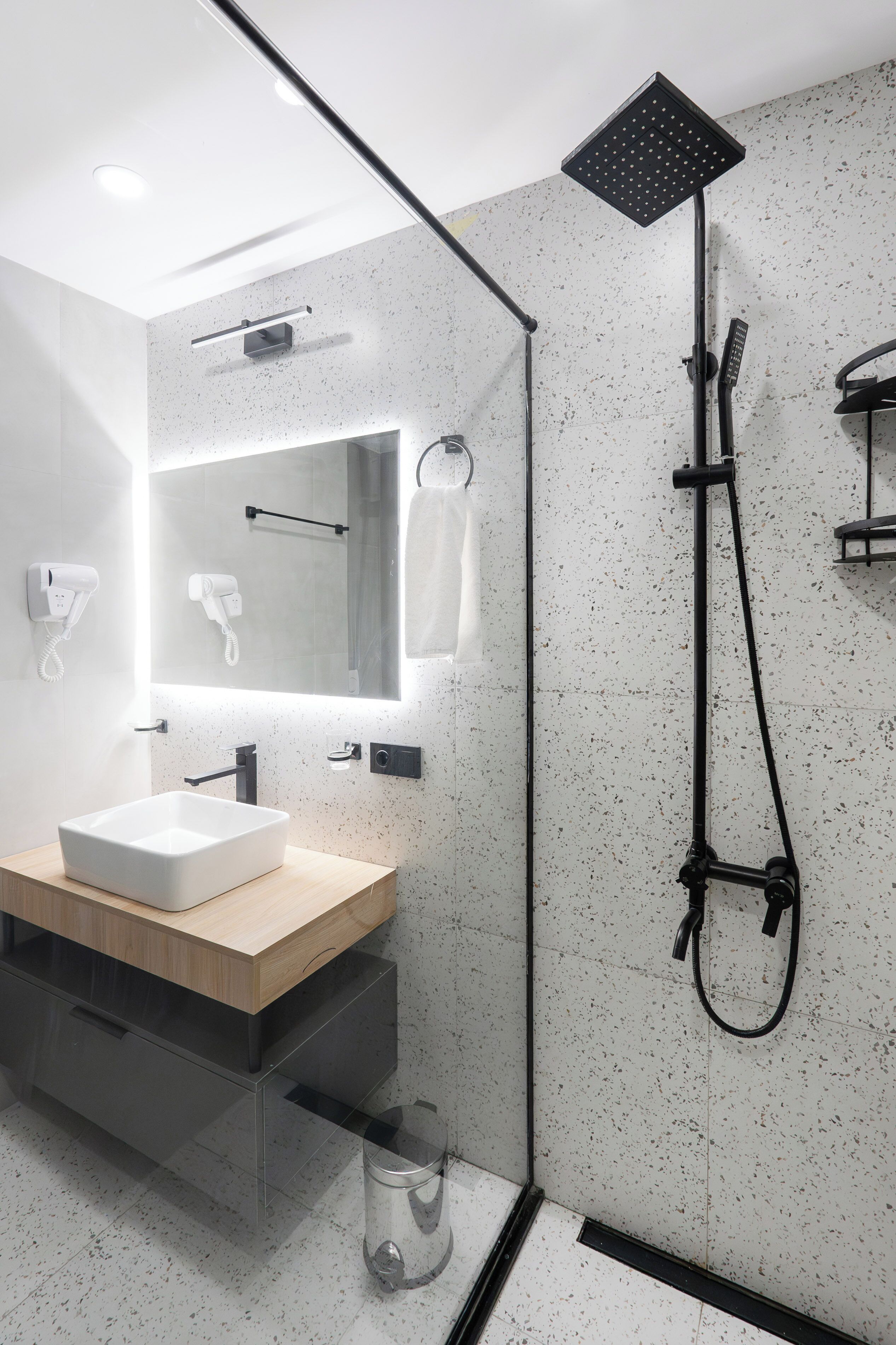 A modern bathroom with a freestanding sink, a handheld showerhead, and a towel rack.
