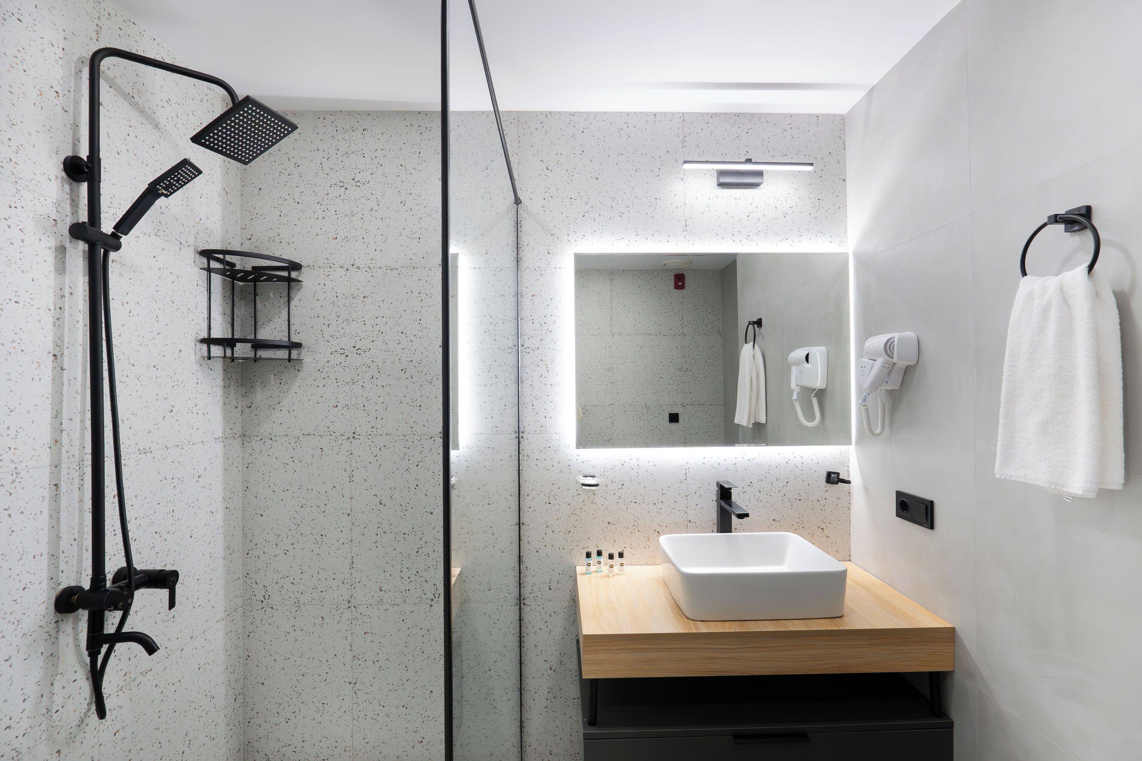 Un baño moderno con ducha independiente, lavamanos y espejo.