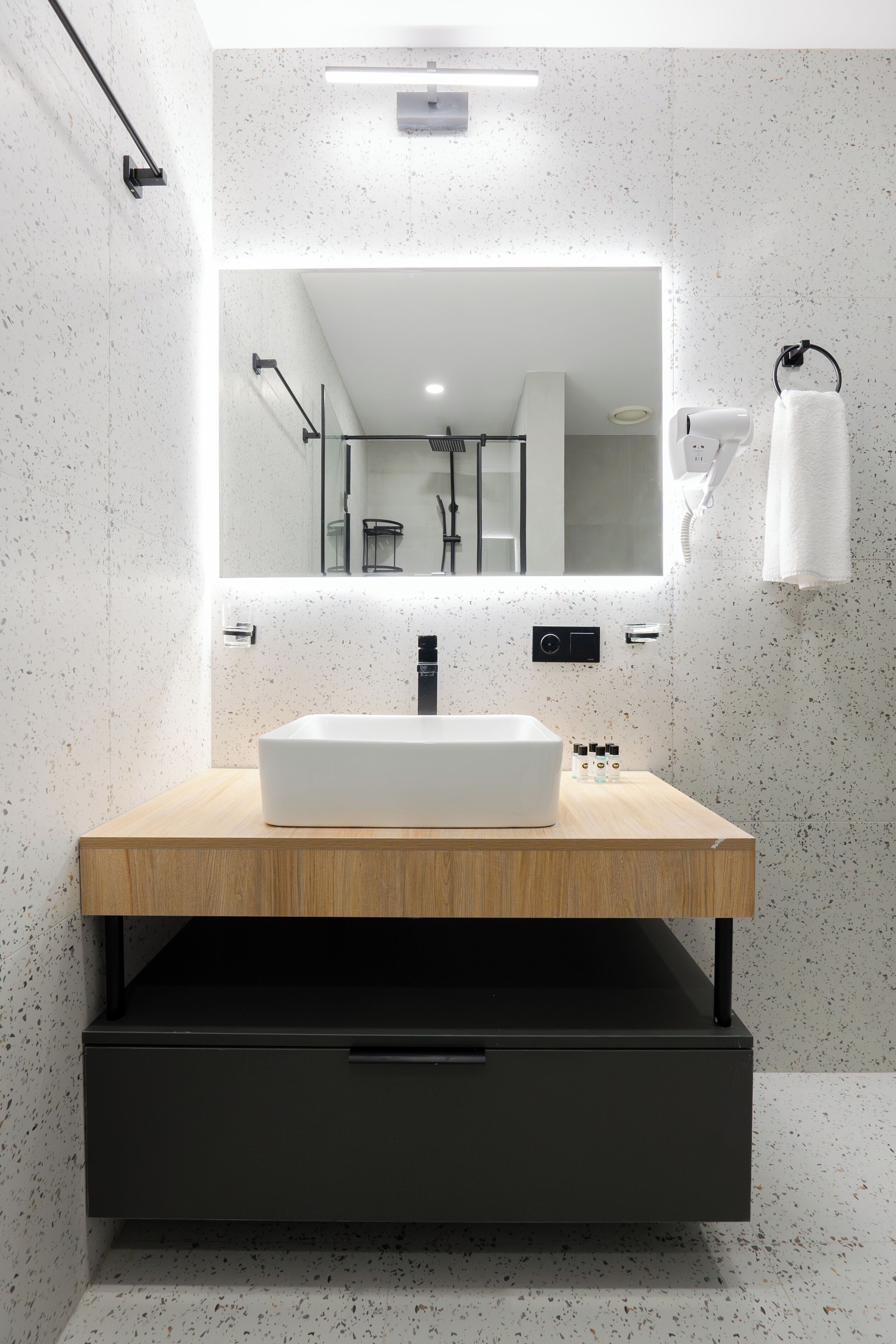 Une salle de bain moderne avec un lavabo rectangulaire, un miroir au-dessus et un porte-serviettes fixé au mur.