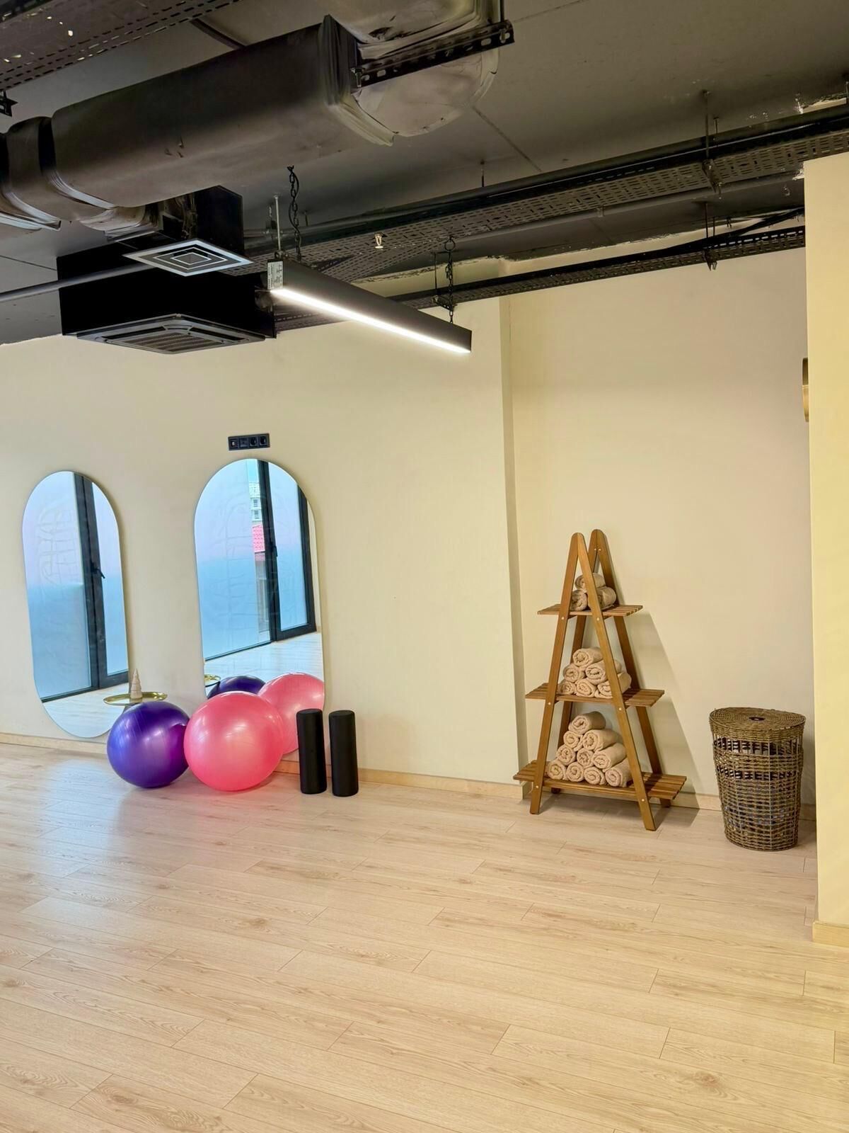 A spacious room with large windows, a wooden ladder, exercise balls, and a woven basket.