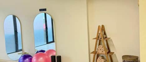 A spacious room with large windows, a wooden ladder, exercise balls, and a woven basket.