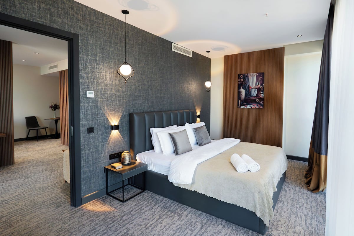 Une chambre d’hôtel moderne avec un grand lit, une table de chevet et une petite table d’appoint.