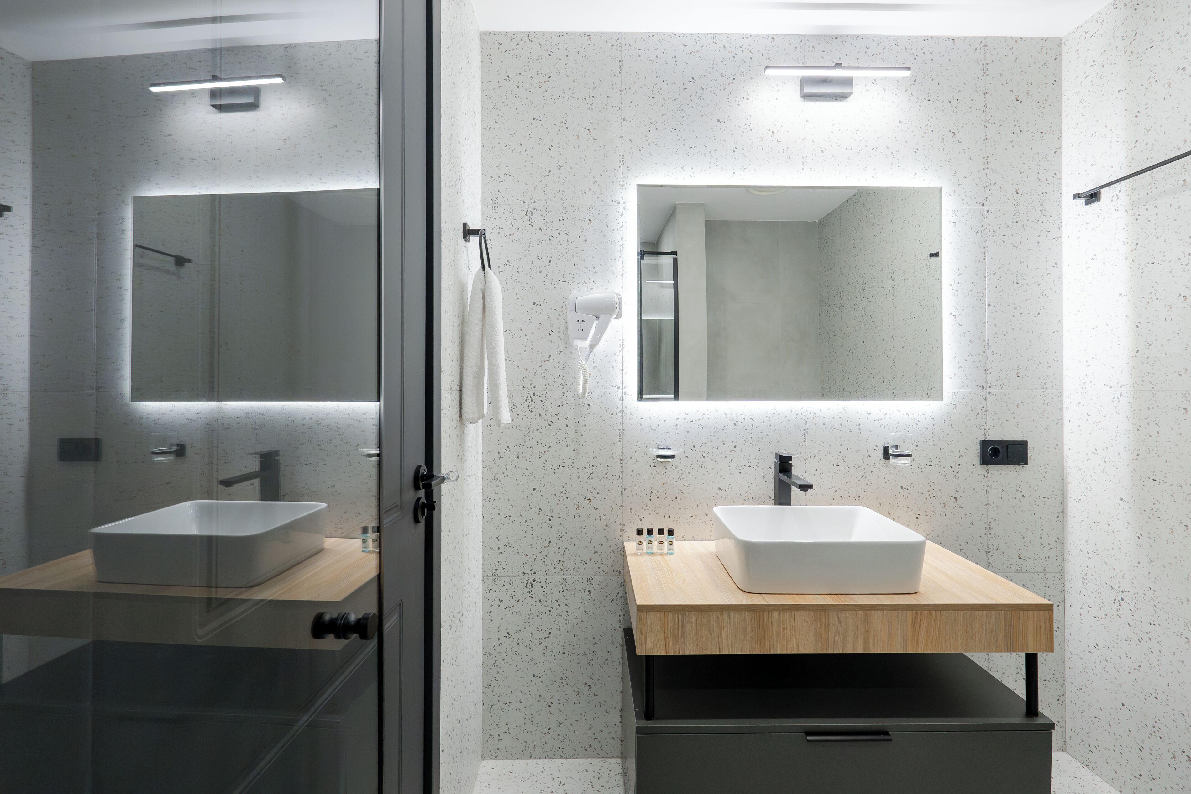 A modern bathroom with two sinks, a large mirror, and a glass shower enclosure.