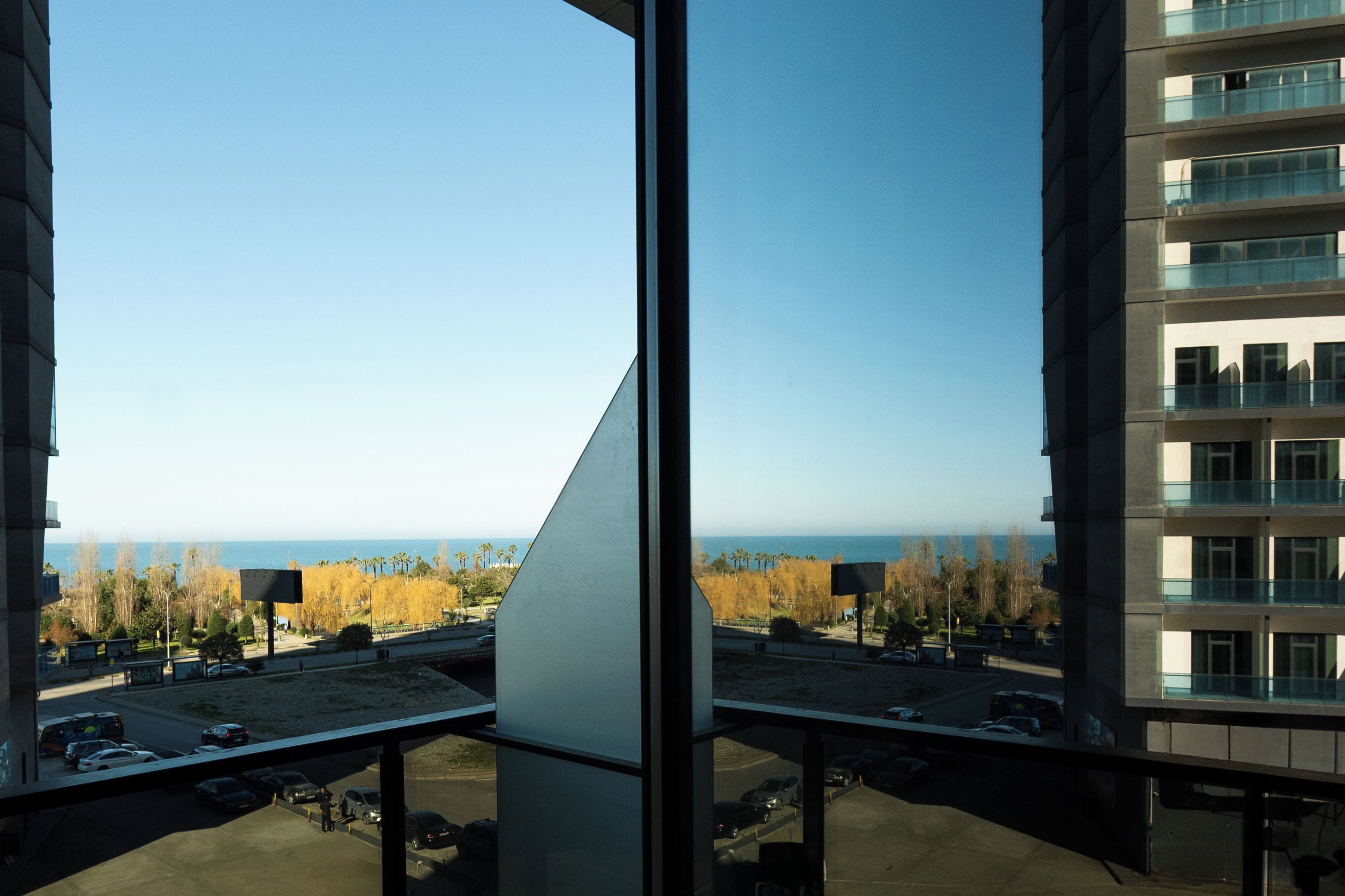 A view from a high-rise building overlooking a parking lot and a body of water.