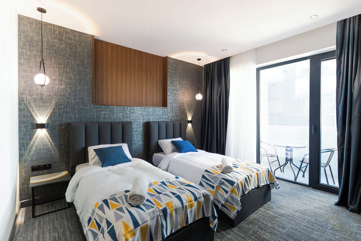 Une chambre d’hôtel avec deux lits, une grande fenêtre et un balcon.