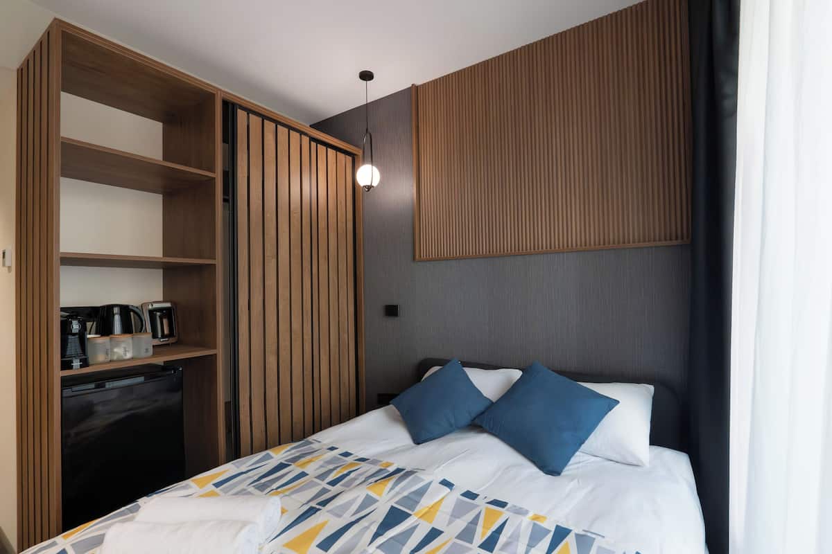 Une chambre d’hôtel comprenant un lit, une armoire, un petit coin cuisine et un panneau fixé au mur.