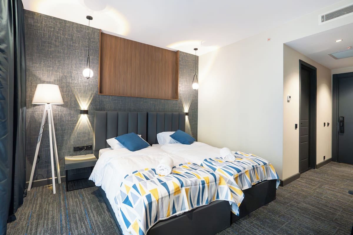Une chambre d’hôtel avec un grand lit, deux tables de chevet, un bureau, une lampe et une armoire.