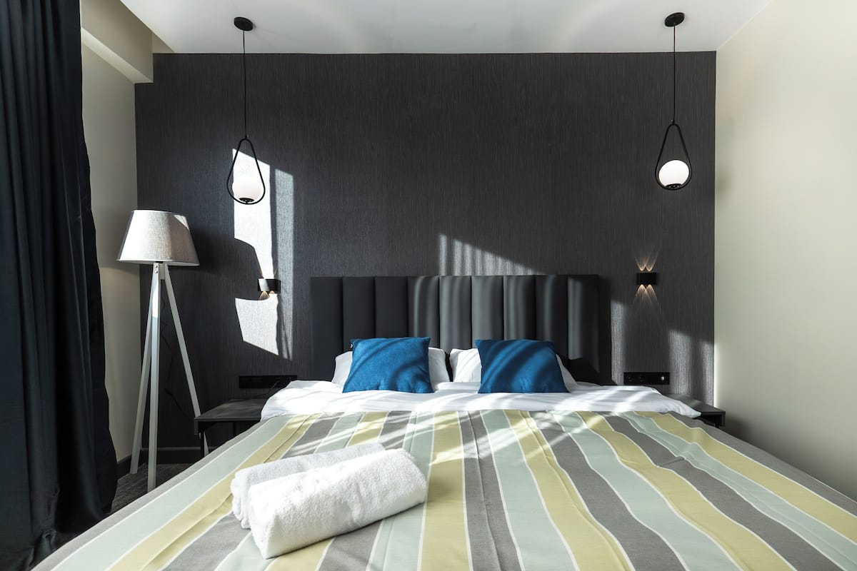 Une chambre d’hôtel moderne avec un grand lit, une table de chevet, une lampe et une tête de lit.