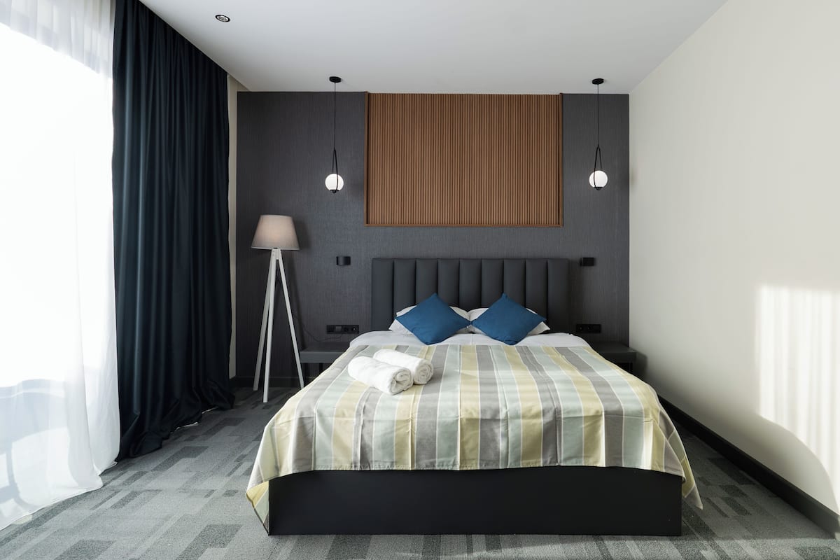 Une chambre d’hôtel moderne avec un grand lit, une tête de lit, deux lampes de chevet et une lampe sur pied.