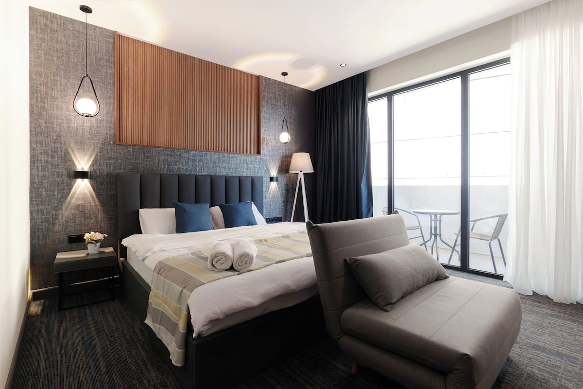 Une chambre d’hôtel moderne dotée d’un grand lit, d’un coin salon et d’un balcon avec vue.